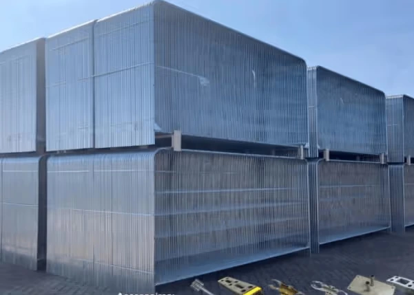 Rack de stockage métallique contenant plusieurs panneaux de clôture arrondis empilés.