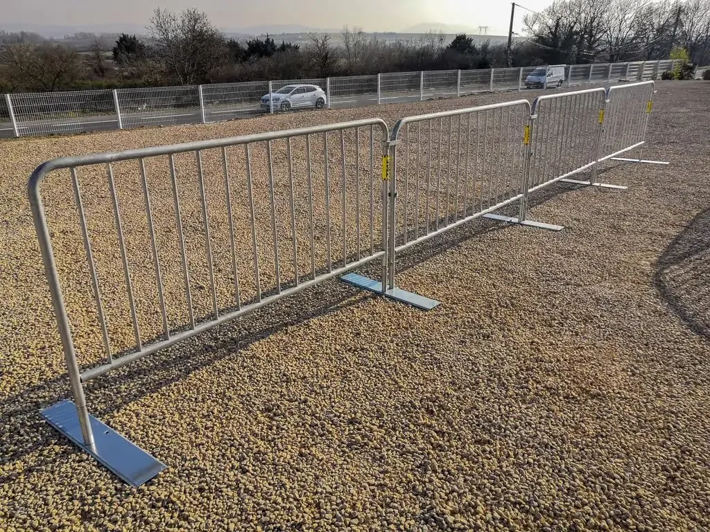 Barrières avec platines de fixation au sol utilisées pour délimiter un espace de travaux ou un événement.