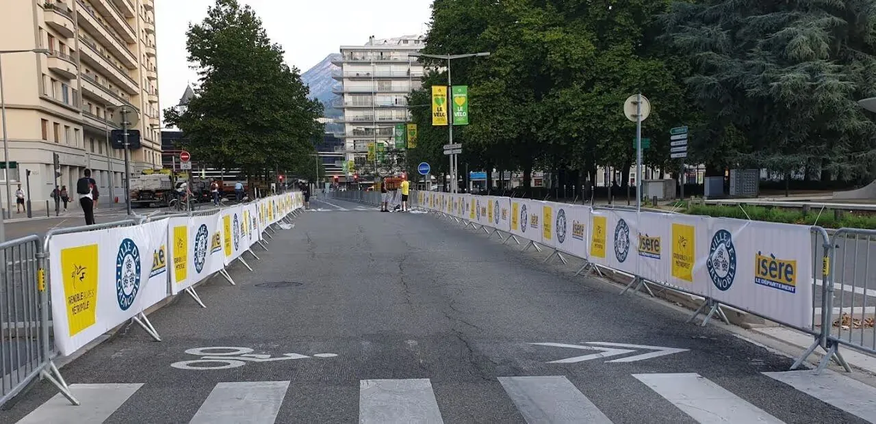 Bâche publicitaire fixée sur une barrière de police type Vauban pour communication événementielle.