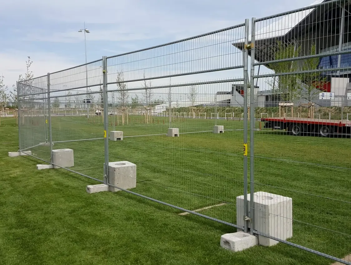 Clôture de chantier mobile installée sur terrain avec pieds béton pour sécurisation de zone événementielle