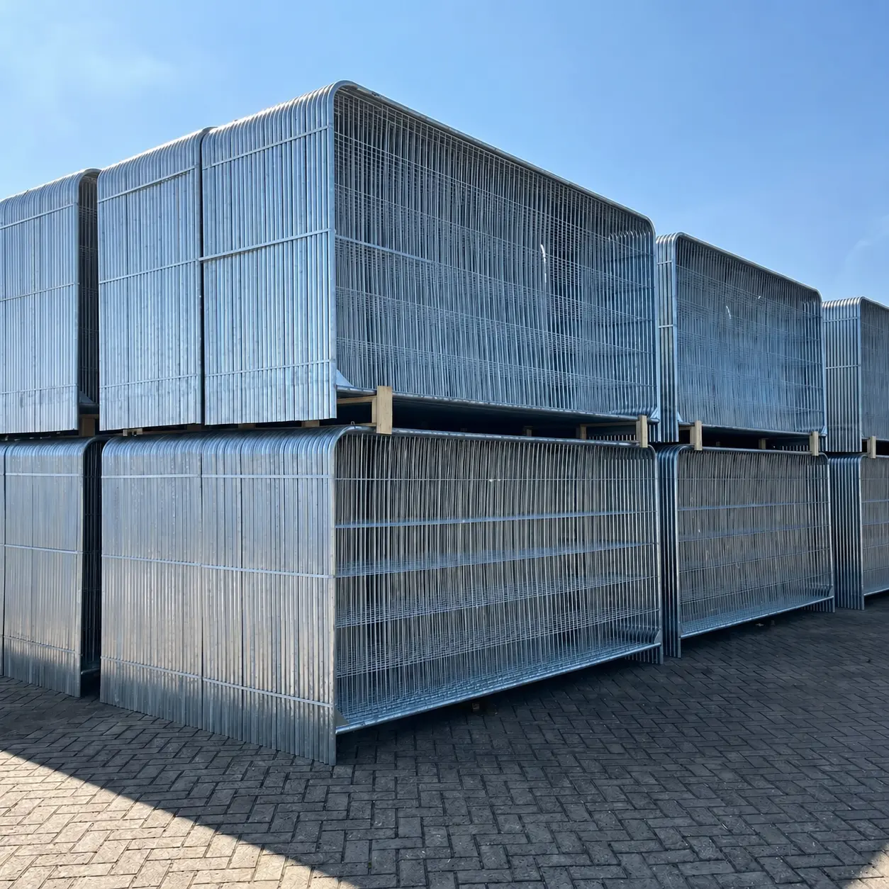 Rack de stockage métallique contenant plusieurs panneaux de clôture arrondis empilés.