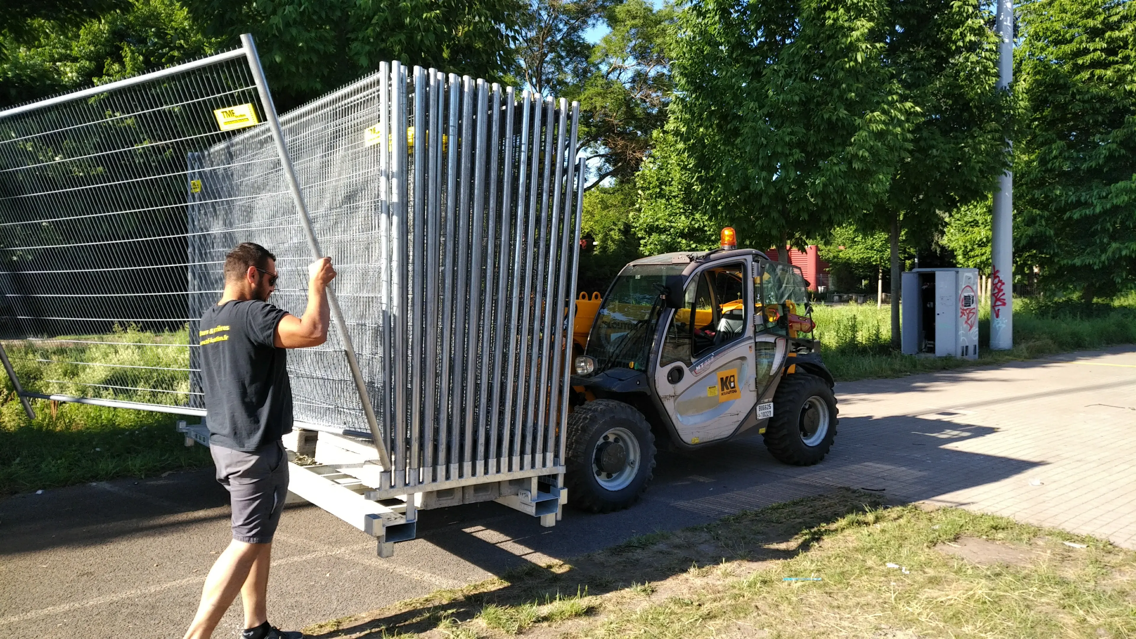 Chargement de panneaux de clôture de chantier sur rack à l’aide d’un chariot télescopique