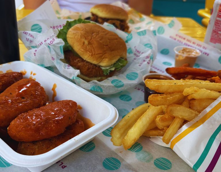 Burger mit Pommes, knusprigen Chicken Wings und Dips als klassisches Fast-Food-Menü serviert.