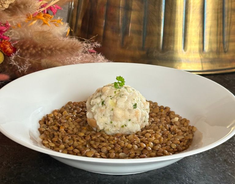 Eingebrannte Linsen mit veganem Semmelknödel auf weißem Teller, traditionelles österreichisches Gericht, schlicht vegan zubereitet