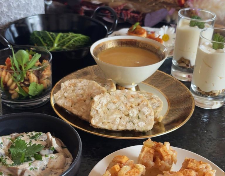 Veganes Catering-Buffet mit Hauptspeisen, veganem Aufstrich, Salat im Glas und Dessertgläsern auf gedecktem Tisch