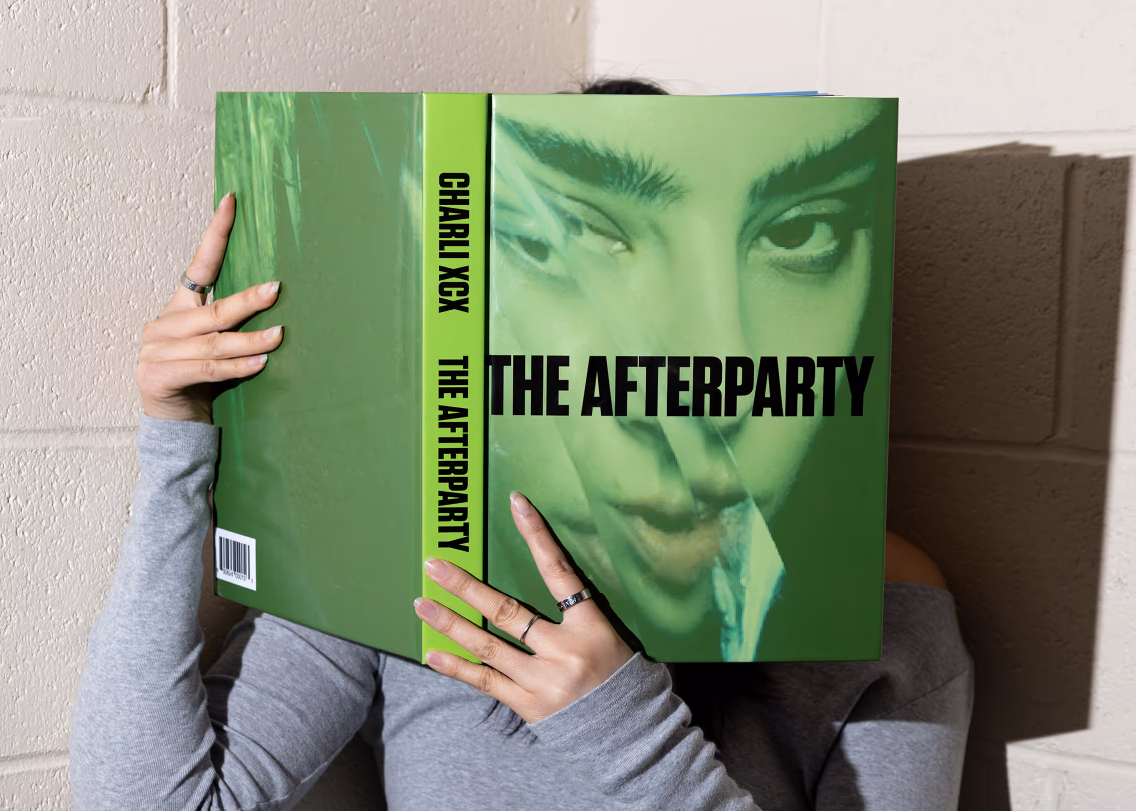 Model reading THE AFTERPARTY book holding it infront of their face - book photo credits to vogue.sg