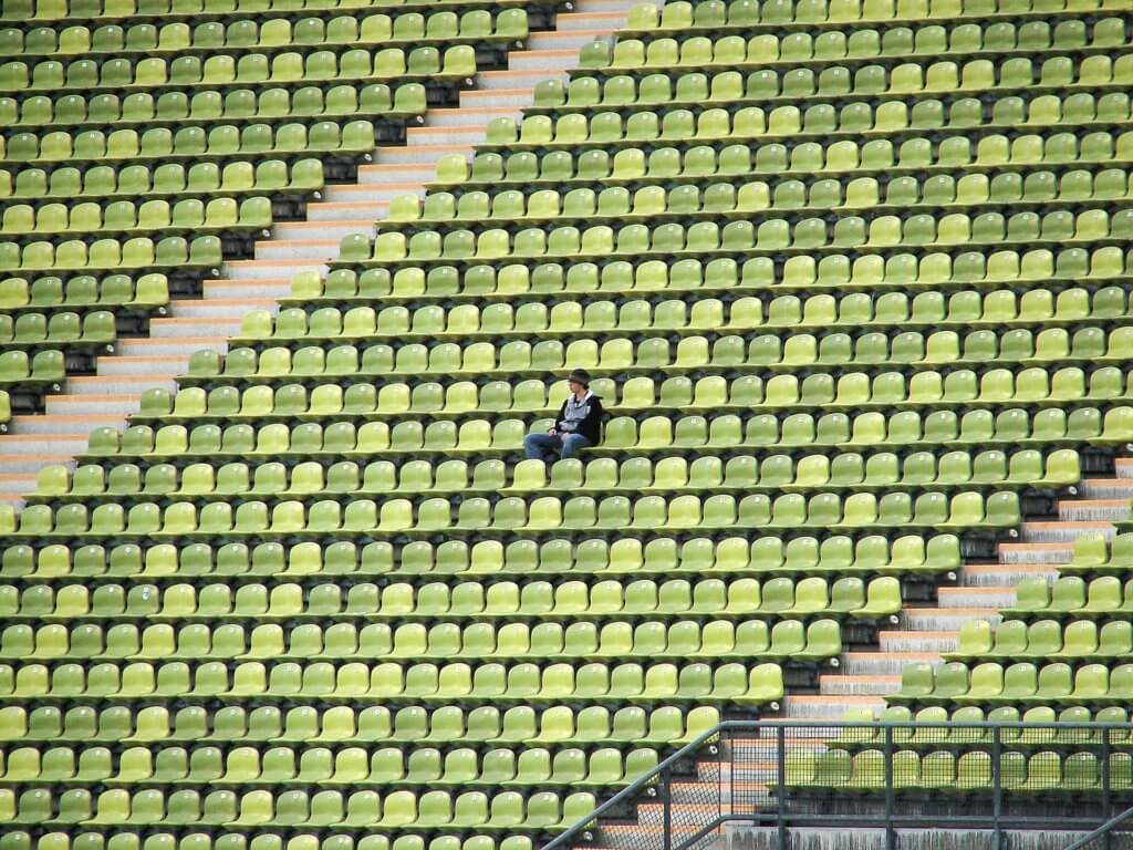 Bullied boy alone in sports stadium feeling isolated.