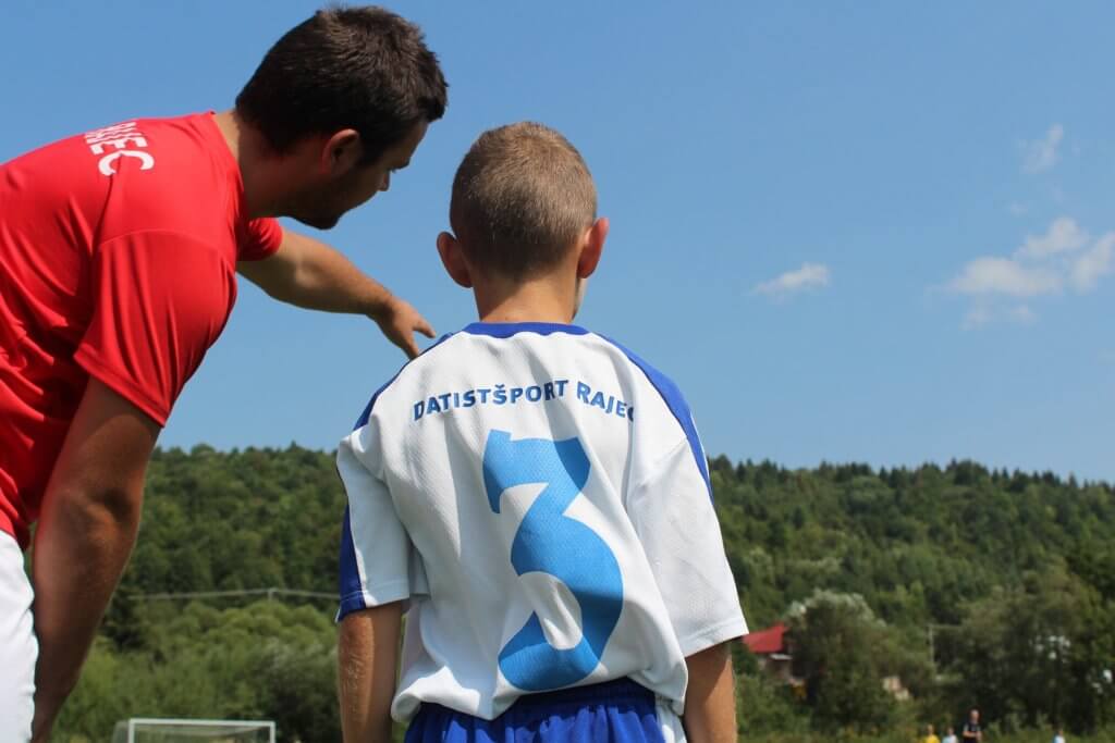 A coach explaining soccer to a child. 
