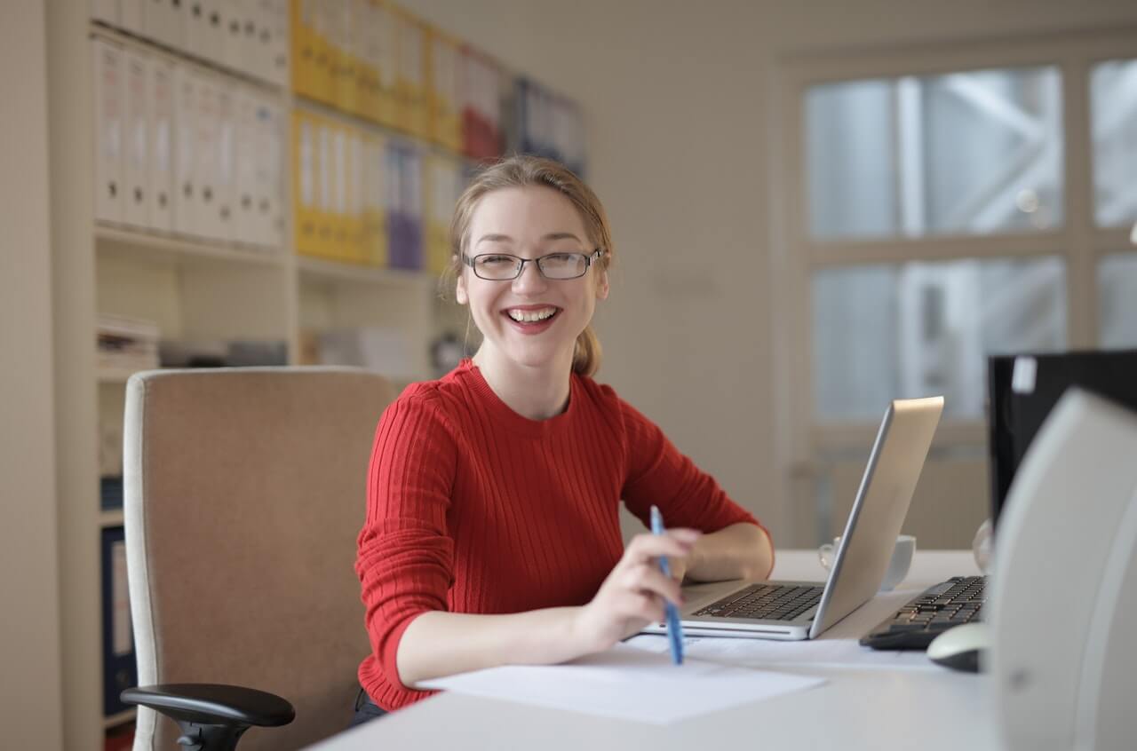 Admin smiling while sitting at her desk.