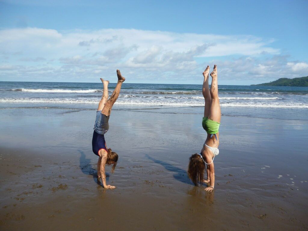 Two friends doing gymnastics on the beach