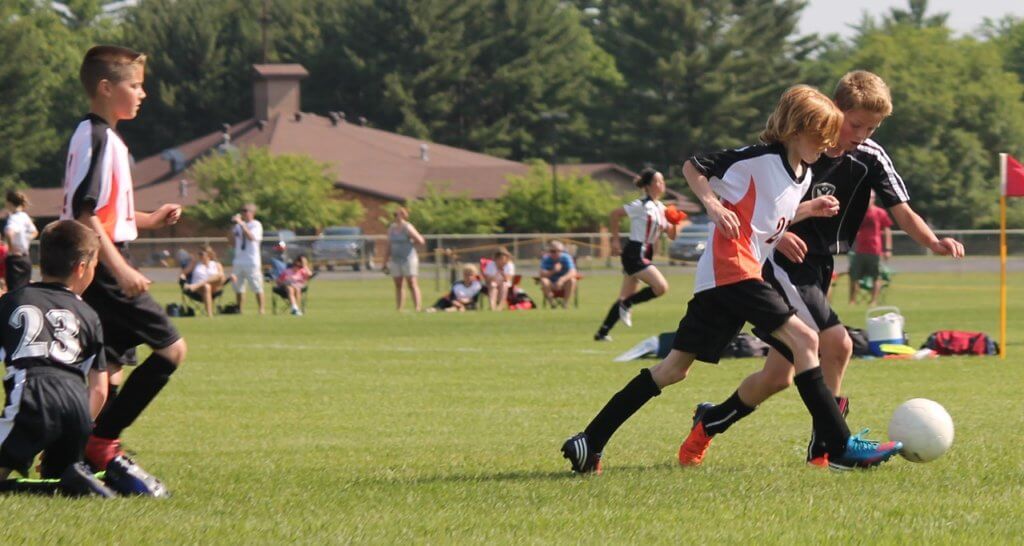 Kids playing soccer together experiencing the social benefits of exercise 