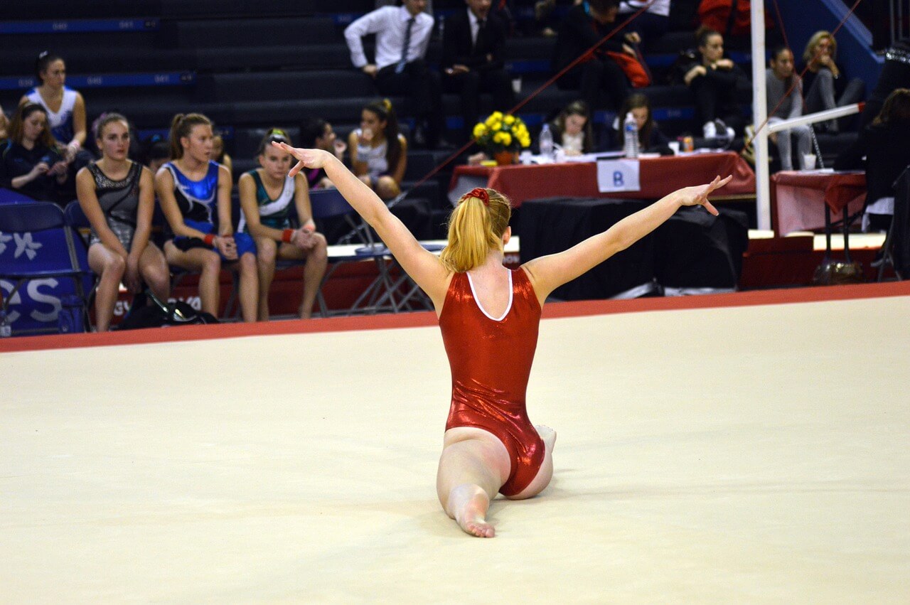 Gymnast performing in front of peers at a competition.