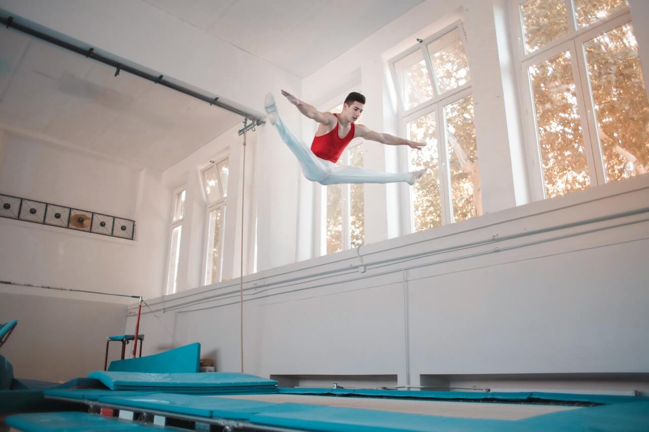 Gymnast performing straddle jump, a beginner gymnastics move on trampoline