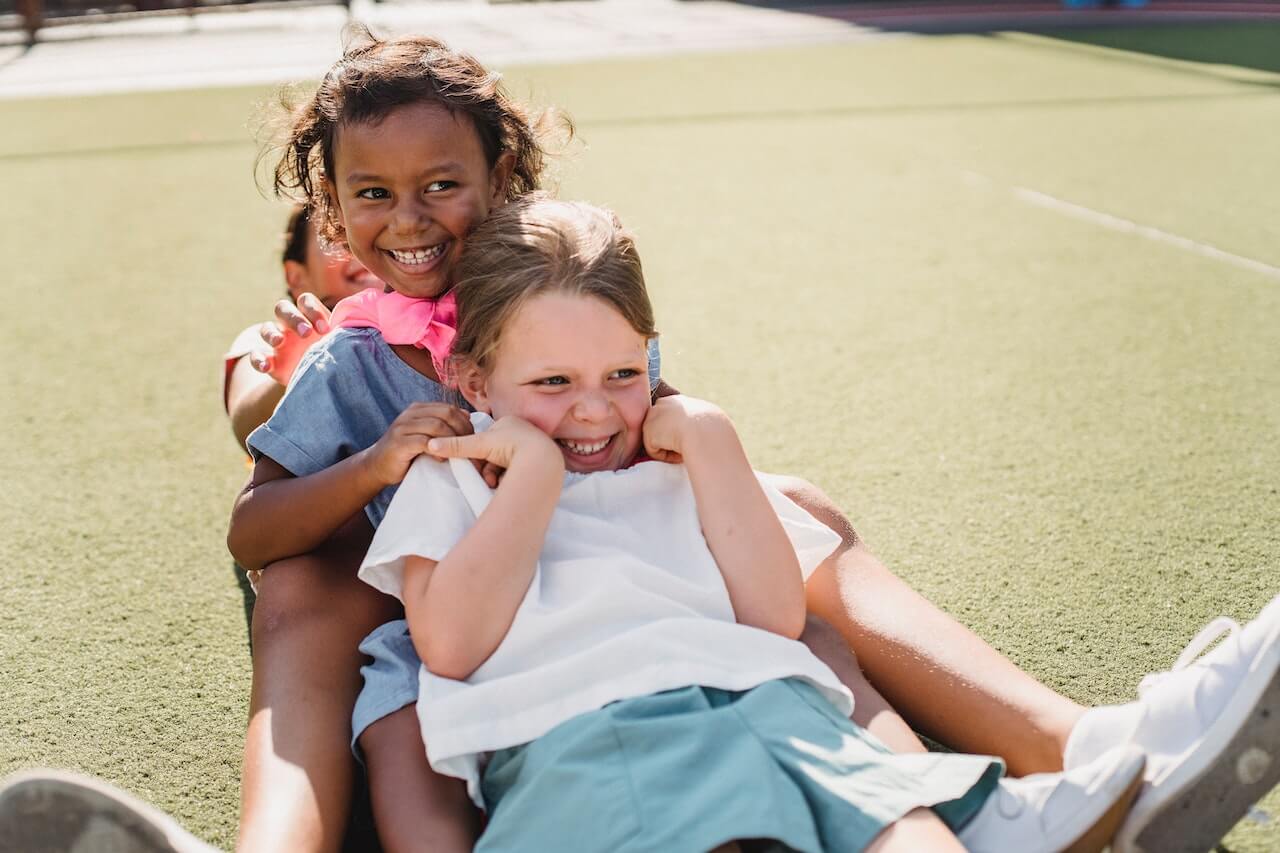 Three girls laughing together playing summer camp games