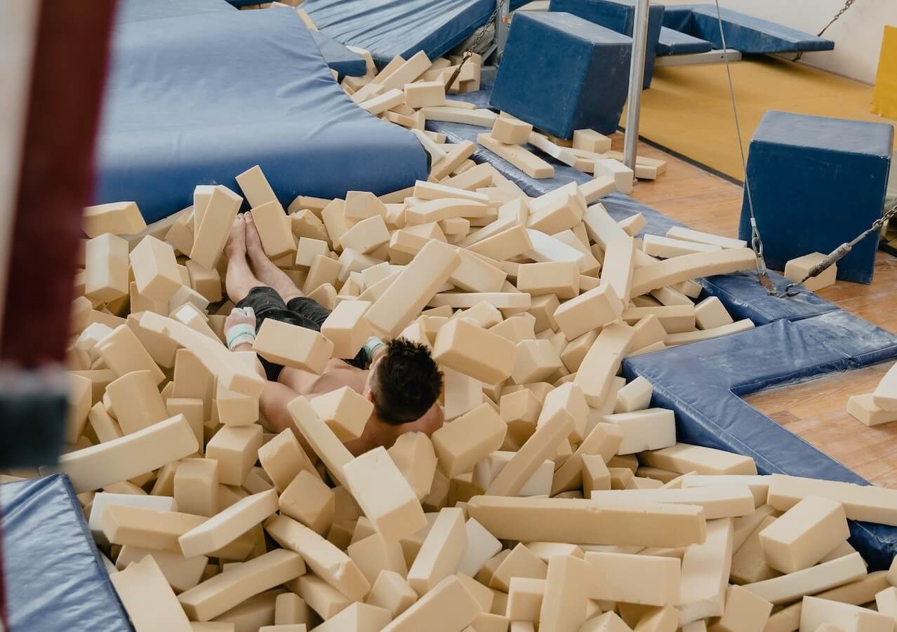 A gymnast sitting in a foam pit.