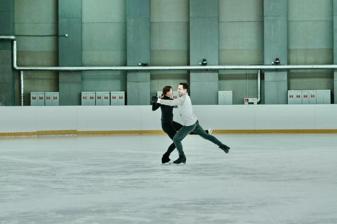 Ice dancers skating together at an indoor ice rink.