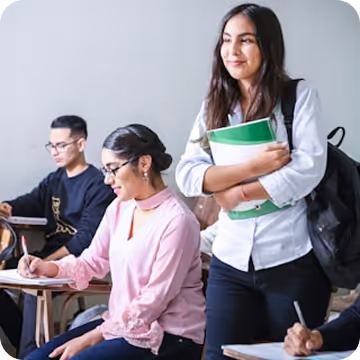 A student standing up in class, holding books.