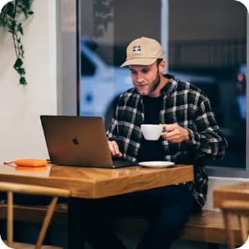 A person working on their laptop at a café.
