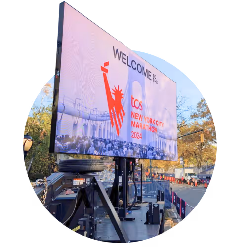 Large digital screen displaying 'Welcome to the TCS New York City Marathon 2024' in an outdoor setup with trees and street visible.