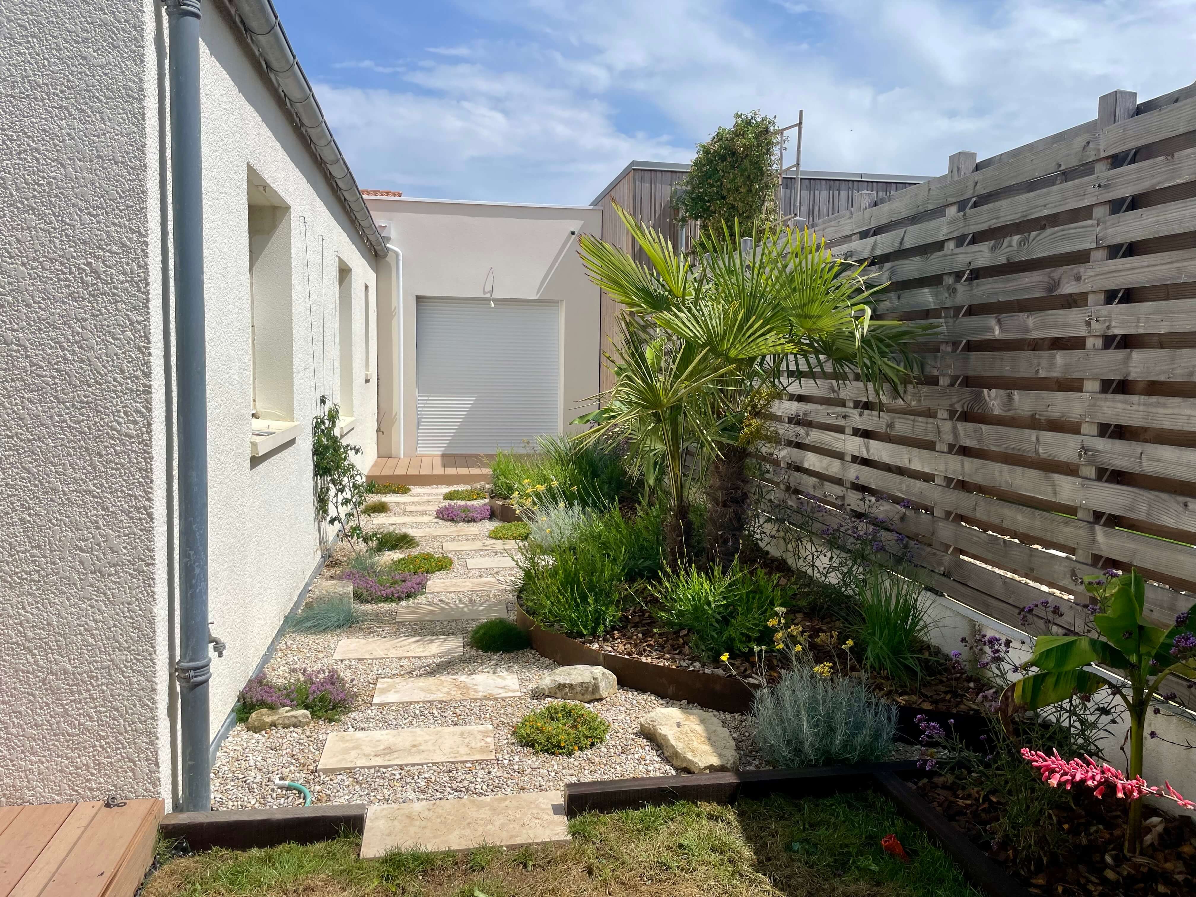 Aménagement paysager d’un jardin avec cheminement en travertin et végétation méditerranéenne