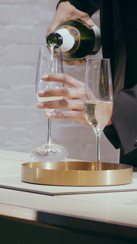 photo of a person pouring champaign into two glasses