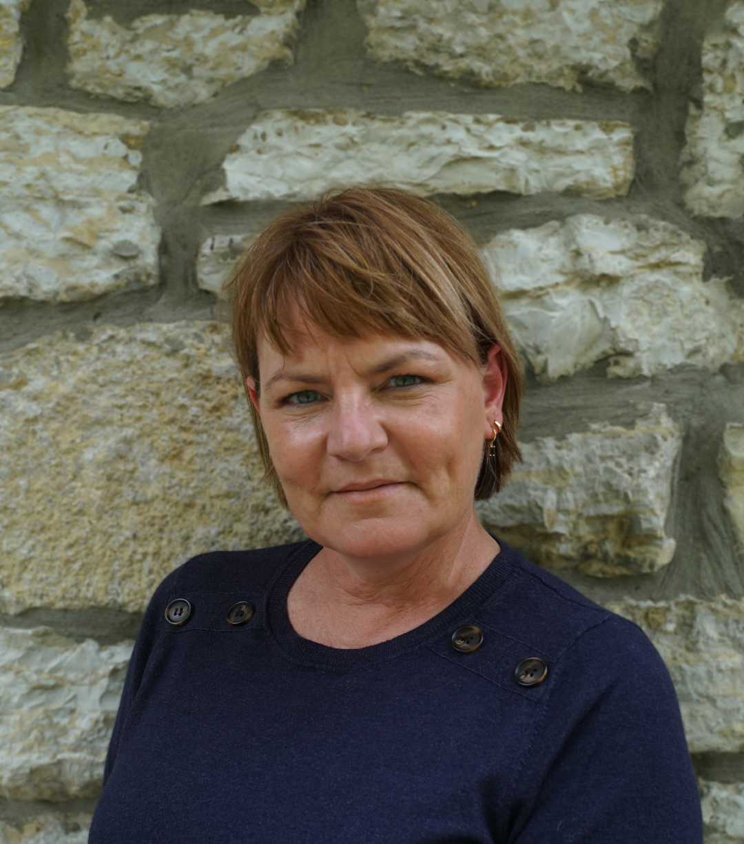 Headshot of middle-aged woman with short dark blonde hair wearing a blue sweater