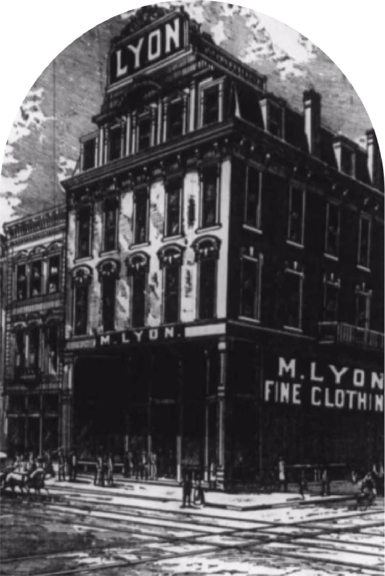 Historic black-and-white illustration of the M. Lyon Fine Clothing building, a multi-story corner structure with ornate architectural details, large windows, and prominent signage reading 'M. Lyon Fine Clothing' across the facade, with pedestrians and horse-drawn carriages visible at the intersection.