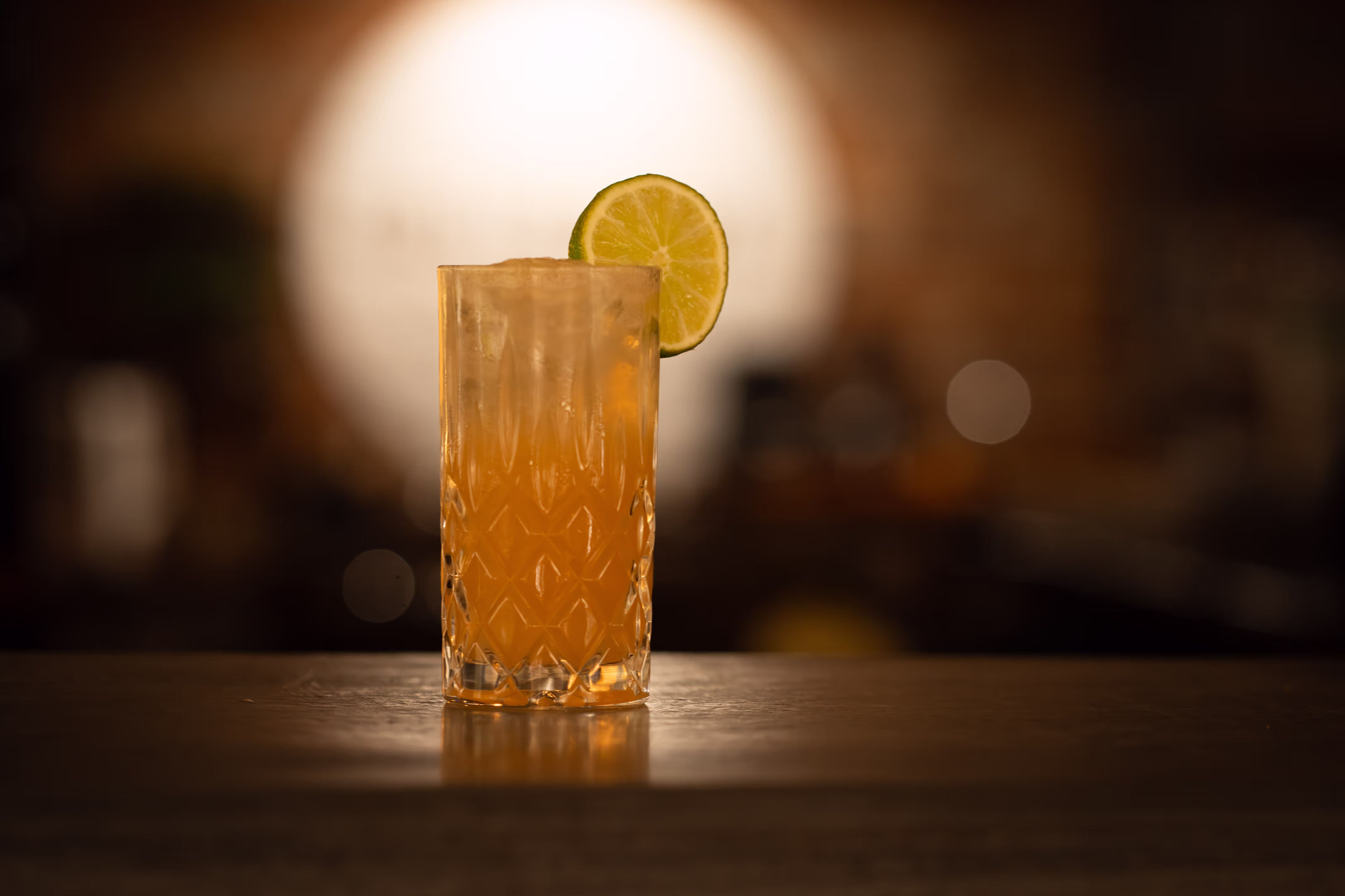 Image of a drink with wedge of lime on the rim. 