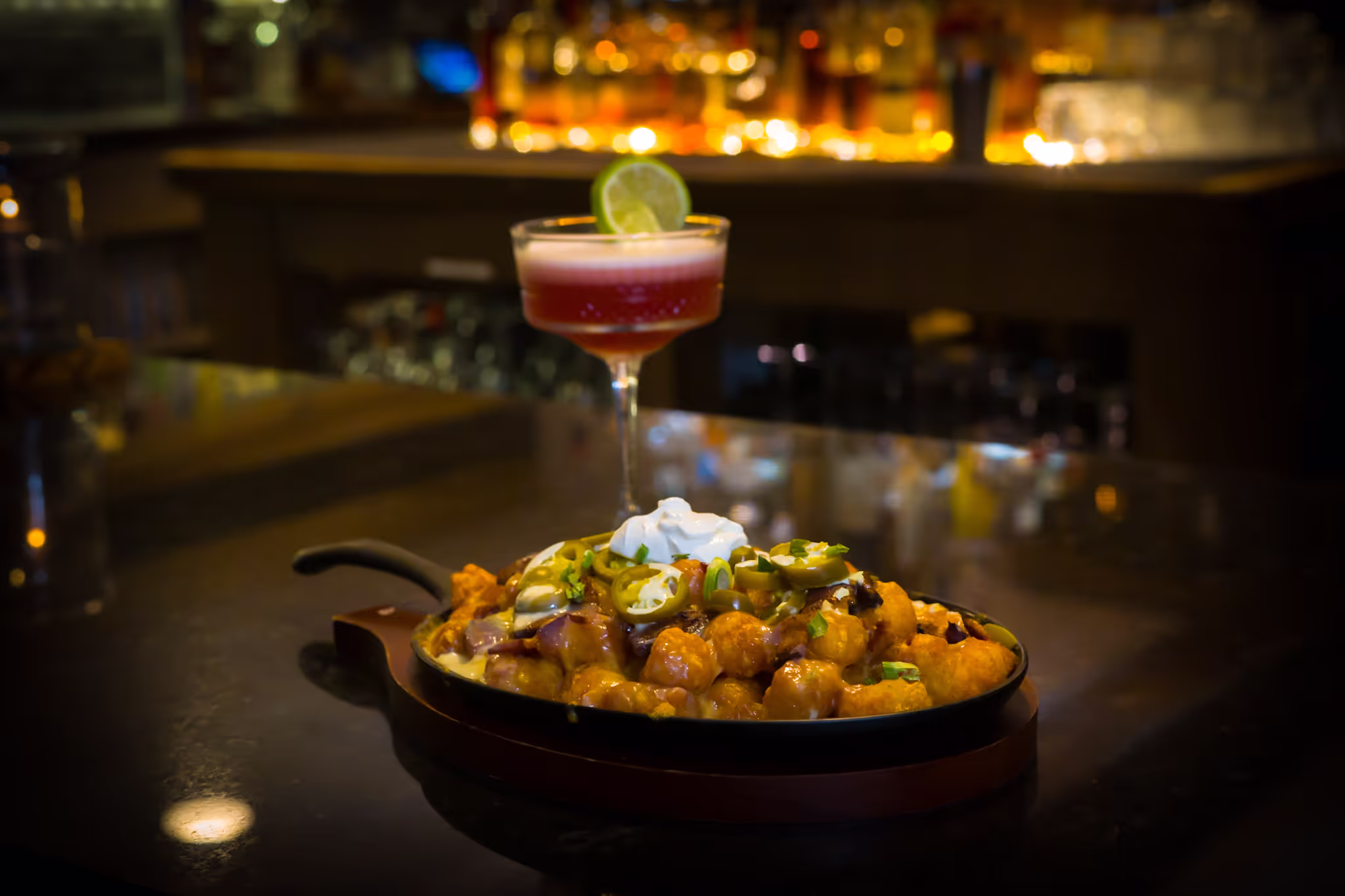 Picture of a dish in a skillet, with a red drink behind.