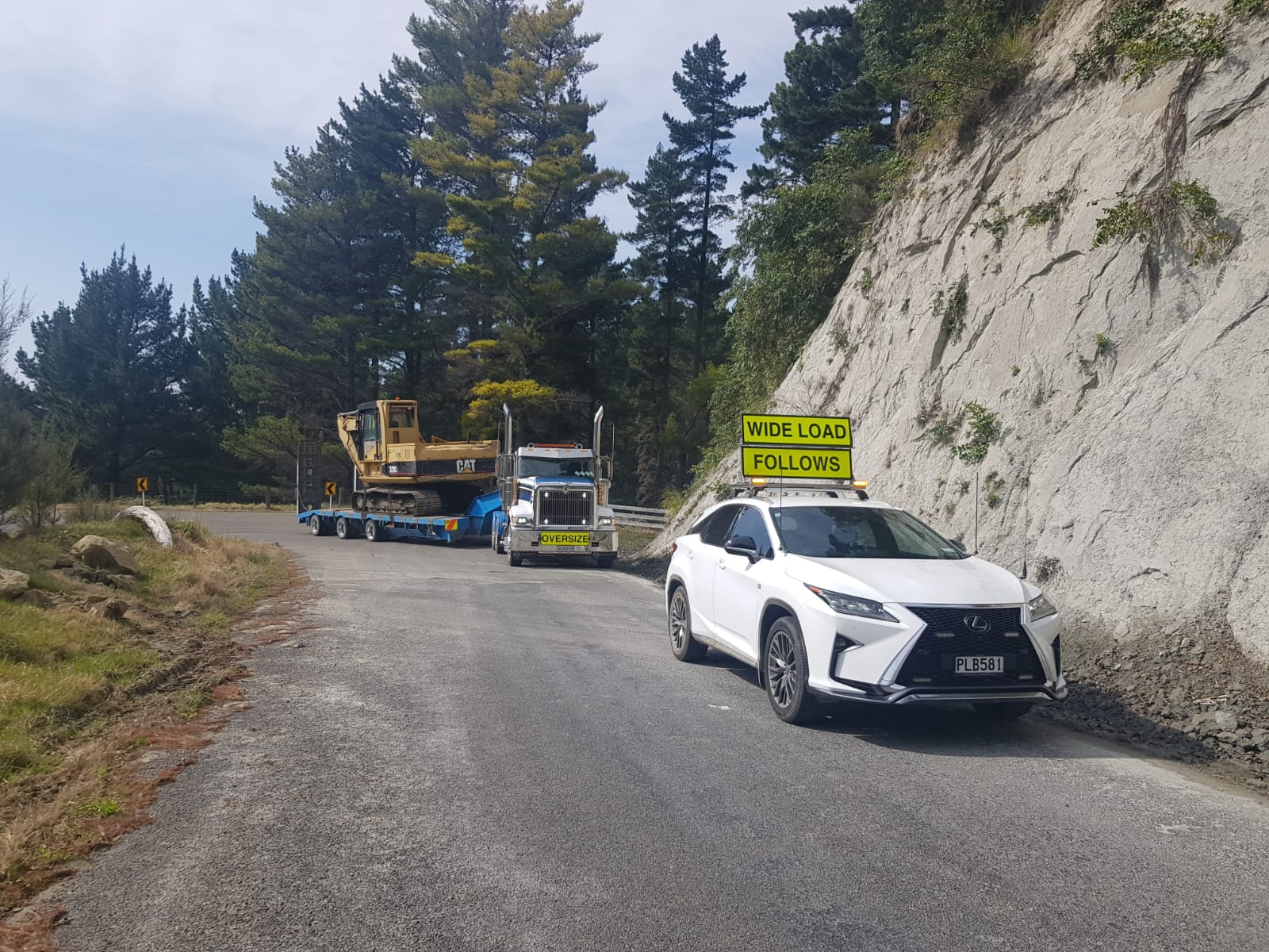 AC98 Heavy Haulage team using a mobile crane to lift and load large steel machinery components onto a Kenworth transporter for delivery across New Zealand.