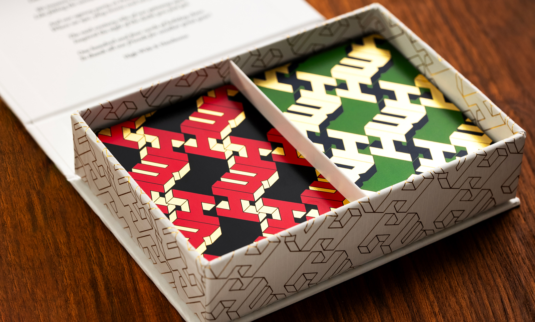 Gift box opened up to show two sets of playing cards, one in black and red, the other green and gold.