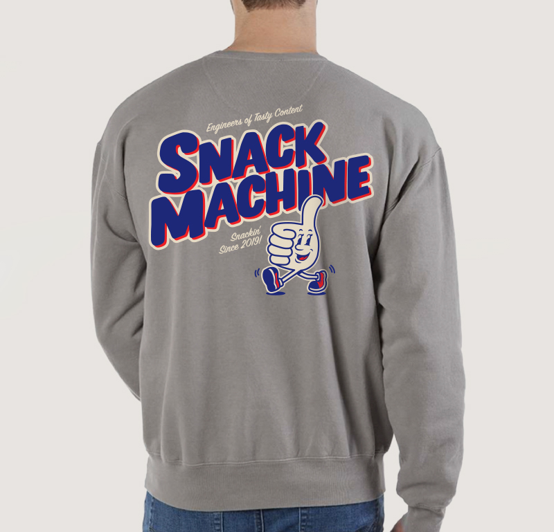 Back of man wearing a gray Snack Machine sweater with logo and smiling hand with thumbs up mascot.