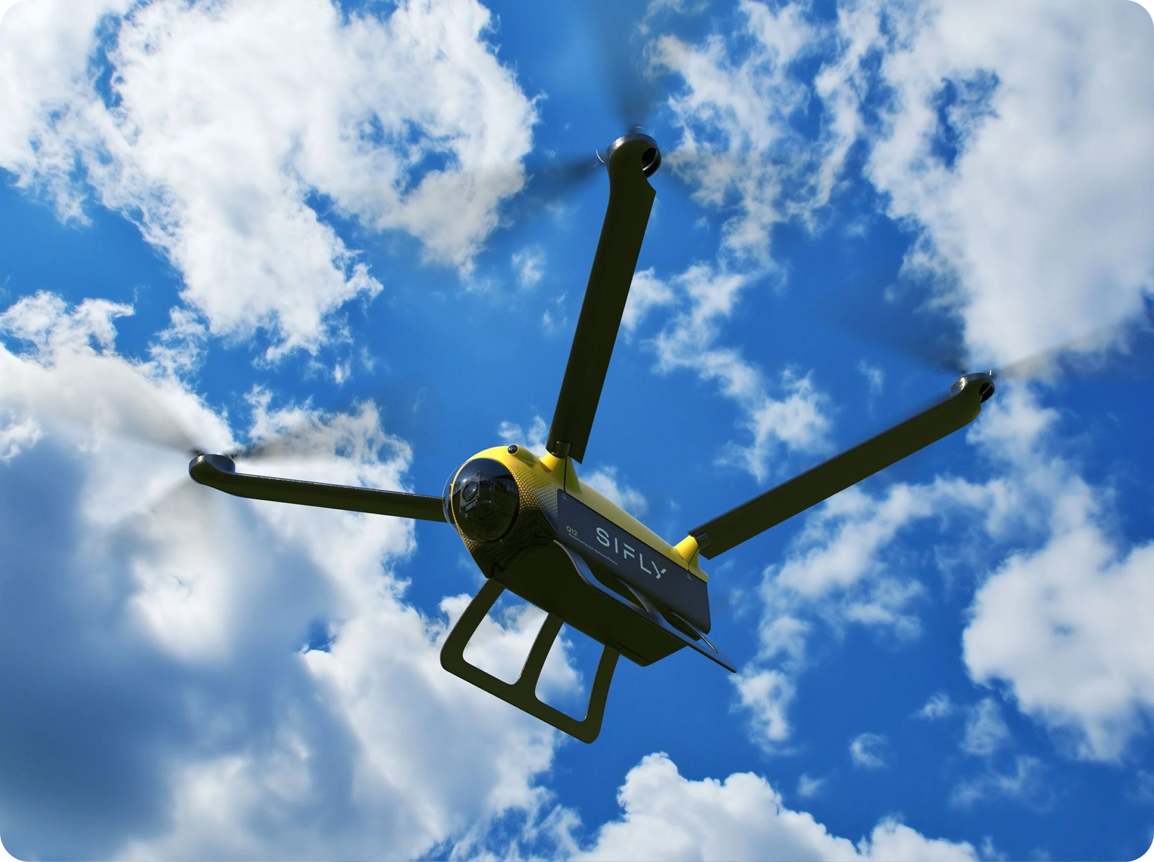 Yellow and black SiFly drone with four propellers flying against a blue sky with scattered clouds.