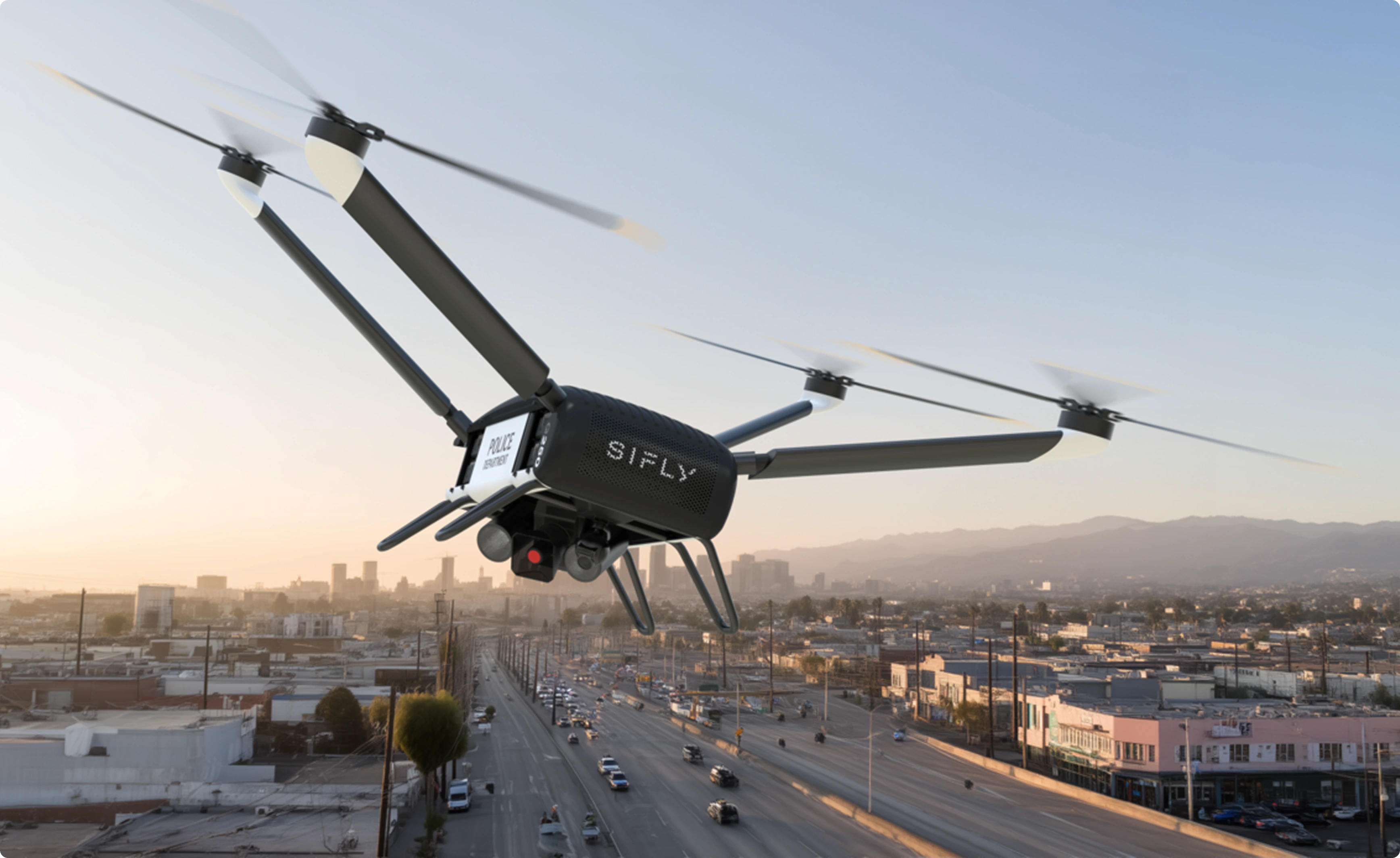 Police drone with four rotors flying over a city street at sunset.