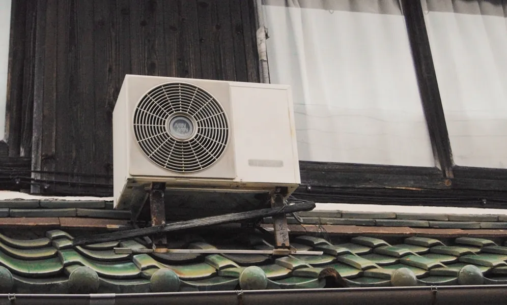 White air conditioning unit mounted on traditional tiled roof exterior wall