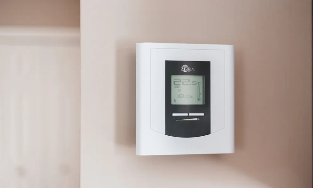 Digital thermostat on wall showing temperature settings
