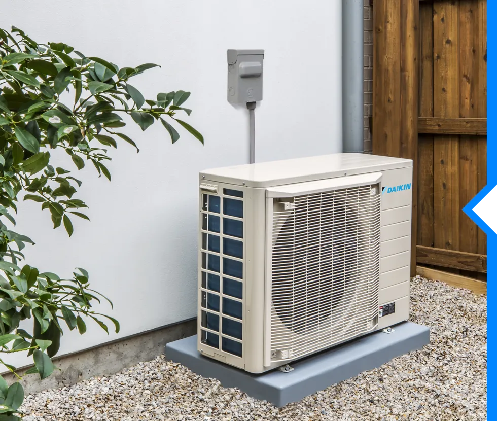 Daikin air conditioning unit installed outside near wooden fence and plants