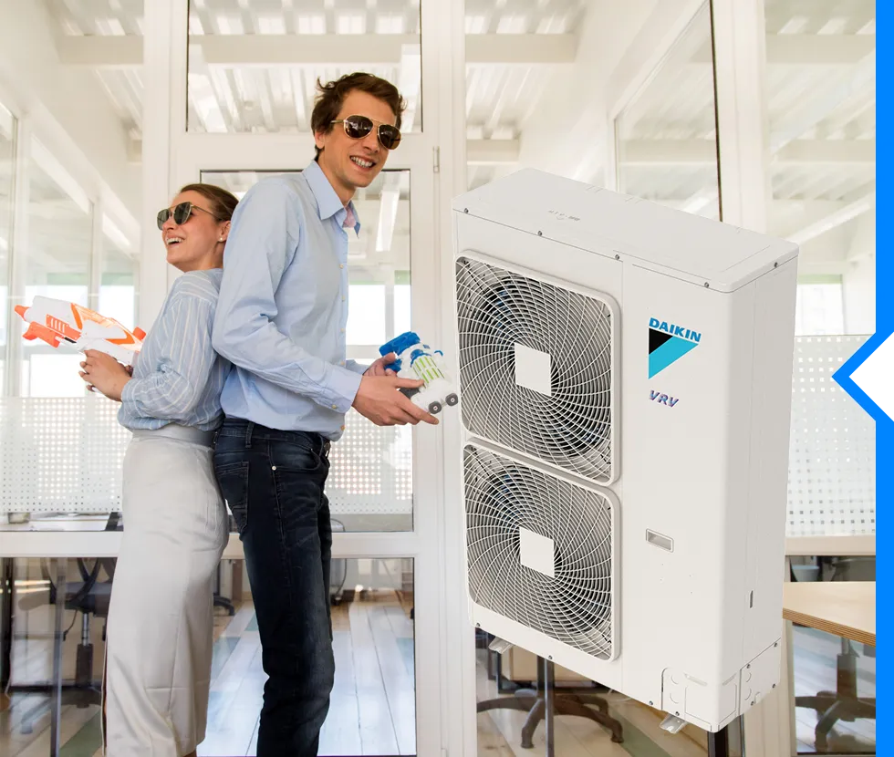 Two people with water guns standing by a Daikin air conditioning unit
