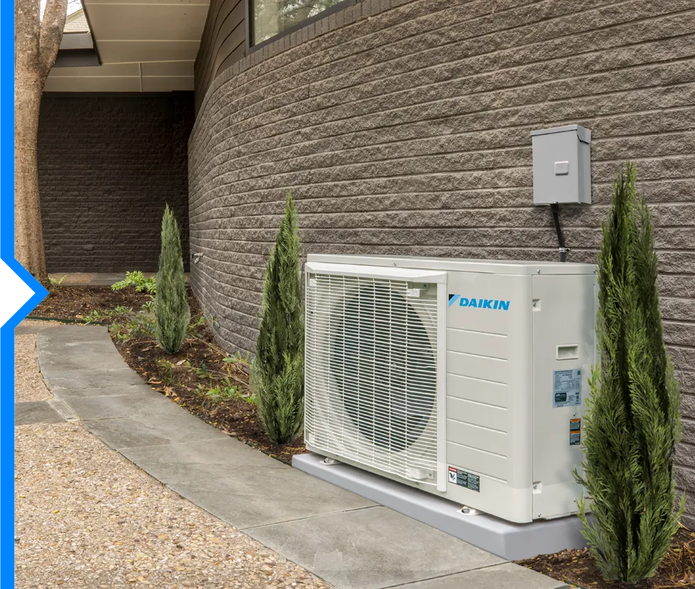 Daikin air conditioning unit installed outside brick building with narrow trees