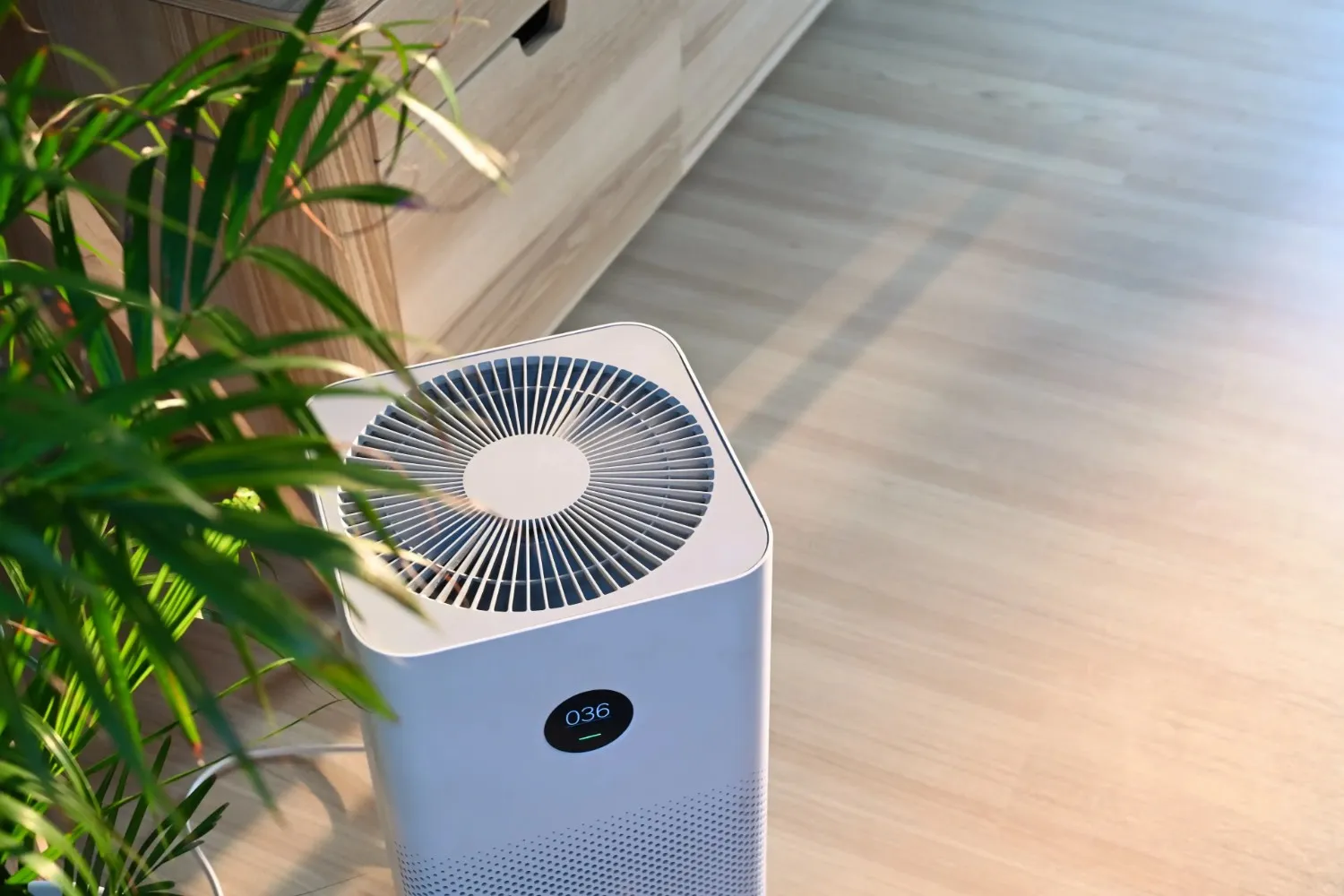 A small air purifier sits on a wooden floor.