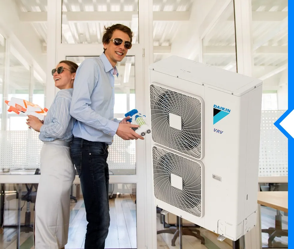 A digitally rendered Daikin VRV air conditioning unit is shown next to two people in an office playing with water guns.