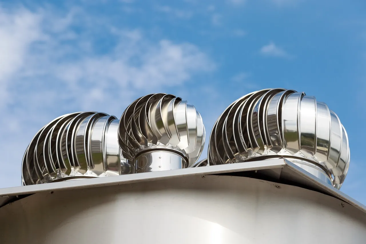 Three metallic turbine vents on a roof against a blue sky