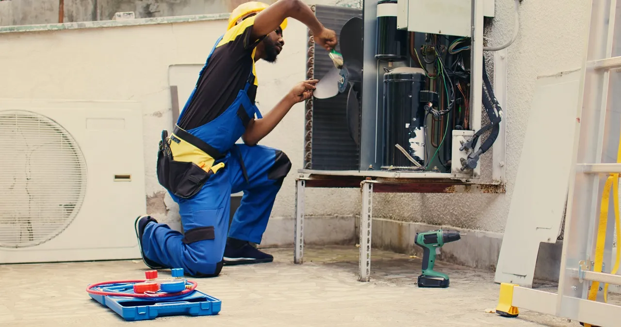 Technician in blue uniform repairing an electrical panel with tools nearby