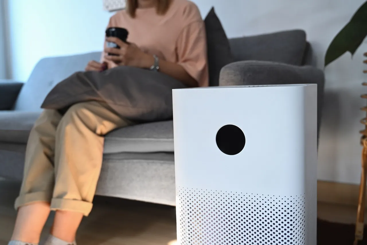 White air purifier on table with person sitting on couch in background