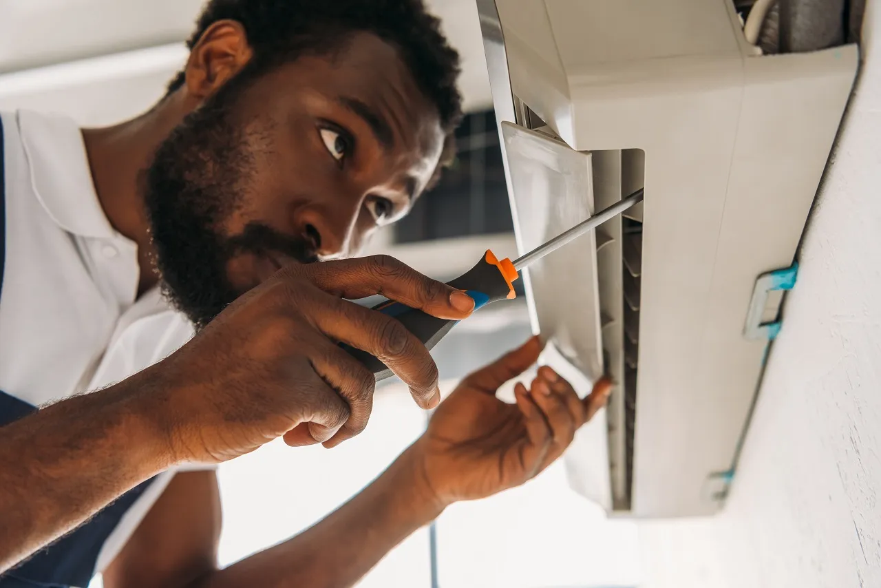 Technician in white shirt repairing electrical panel with screwdriver