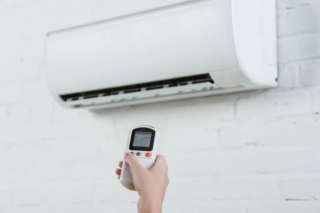 Hand holding remote control for wall-mounted air conditioning unit