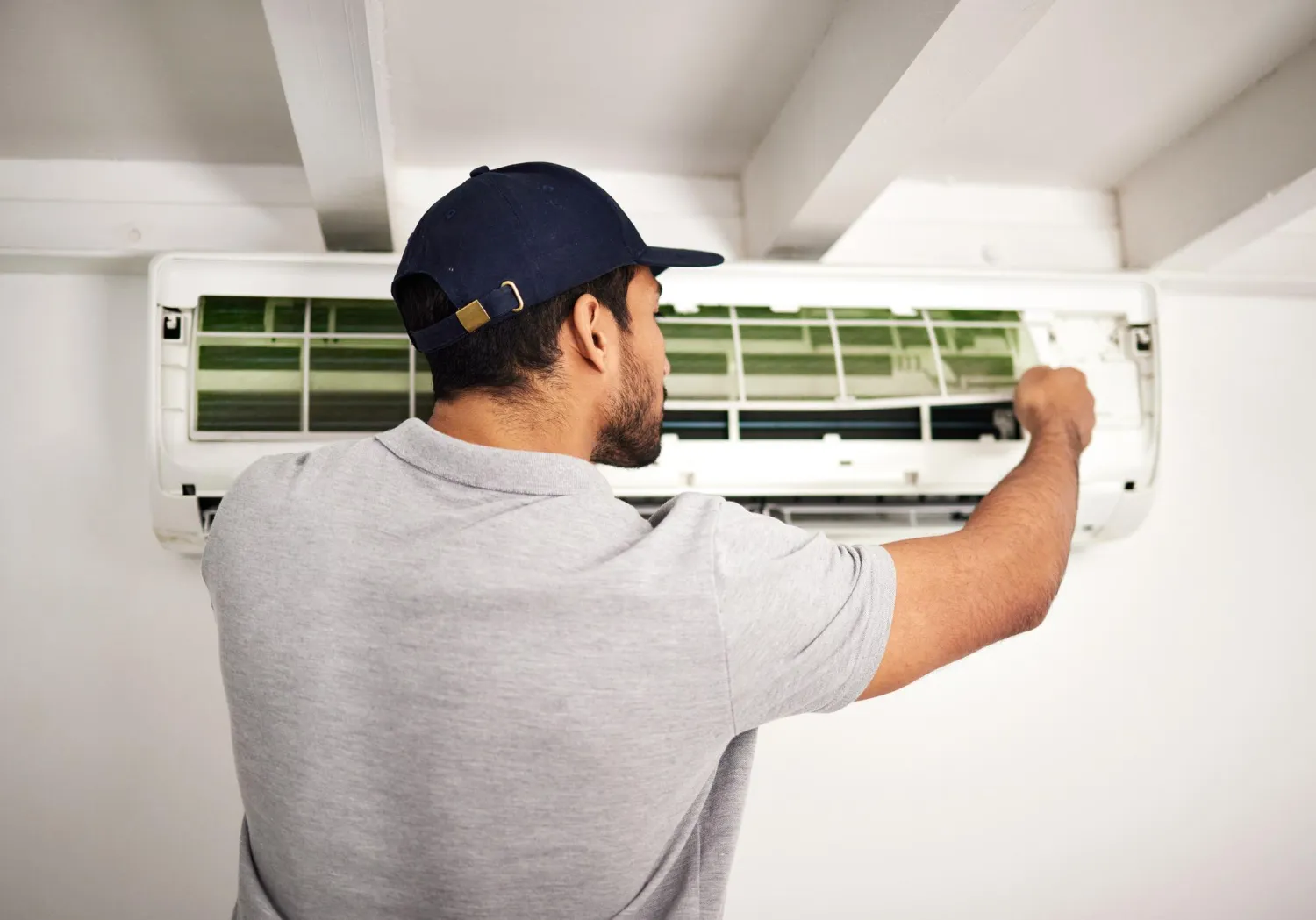 Technician in cap fixing wall-mounted air conditioning unit