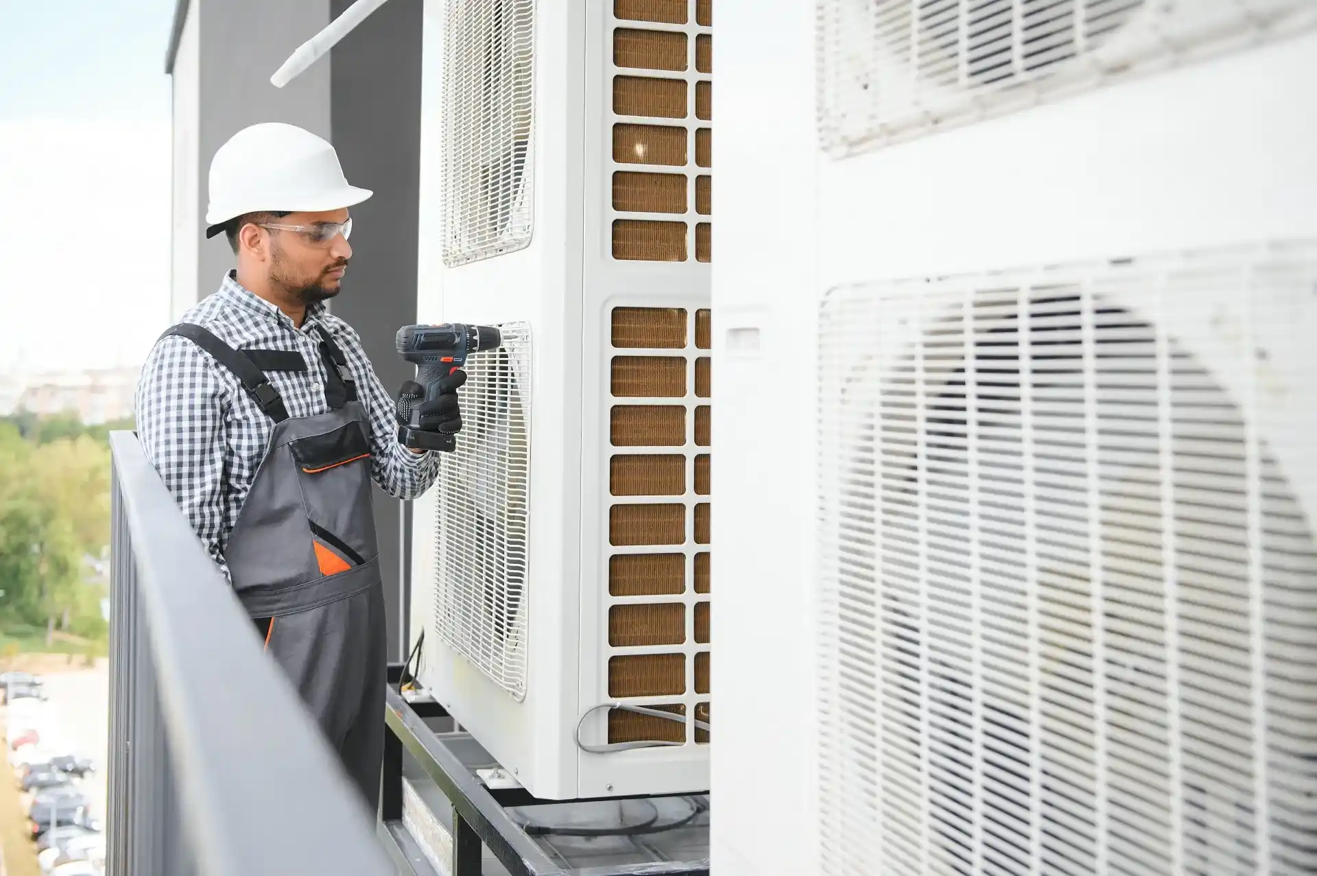 Technician in safety gear installing or repairing an air conditioning unit