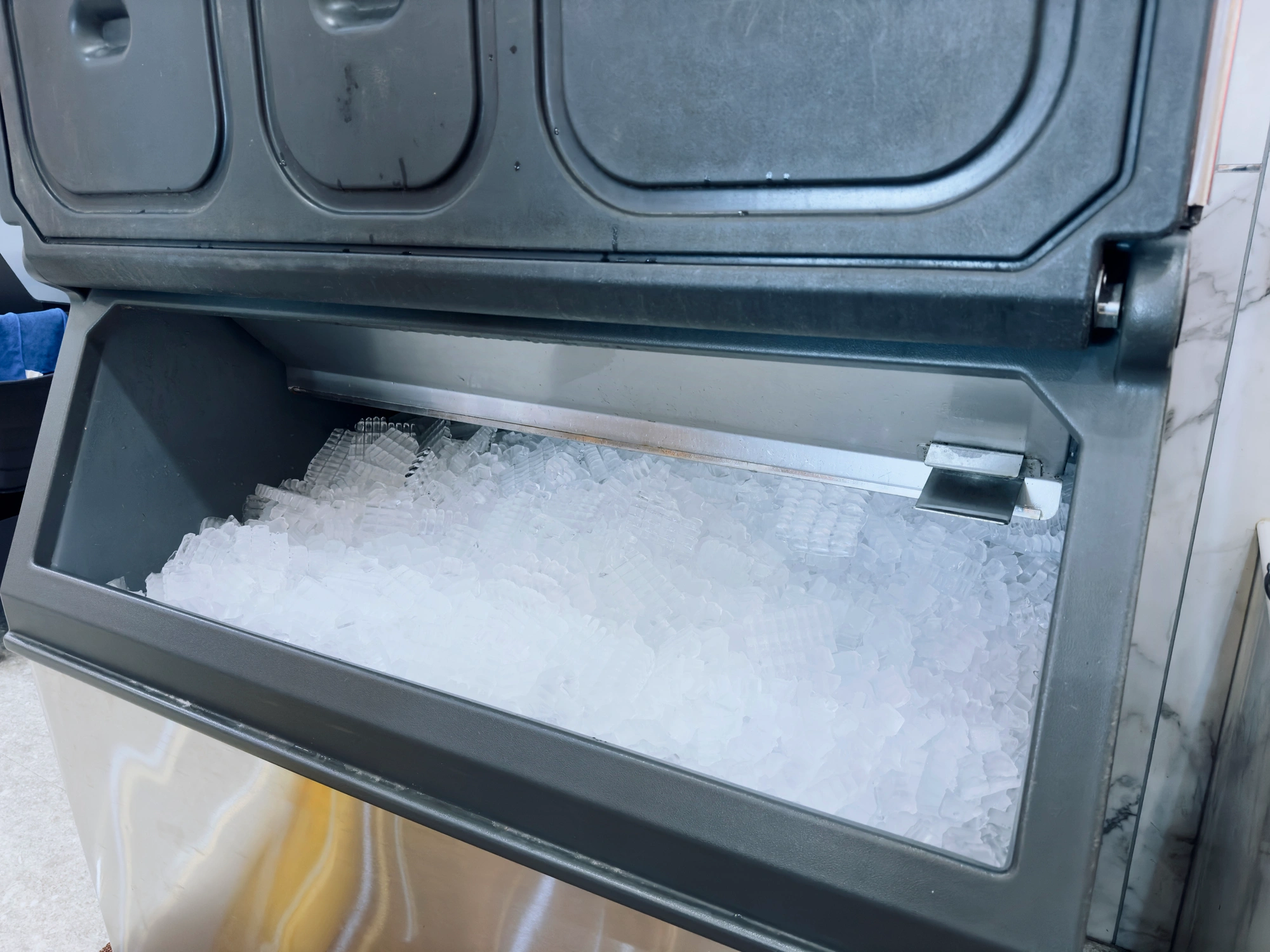 Open commercial ice maker filled with small, uniform ice cubes.