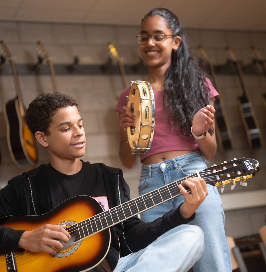 Twee leerlingen maken muziek met gitaar en tamboerijn
